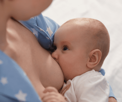 dziecko przytulone do piersi mamy pije mleko, jest wpatrzone w mame